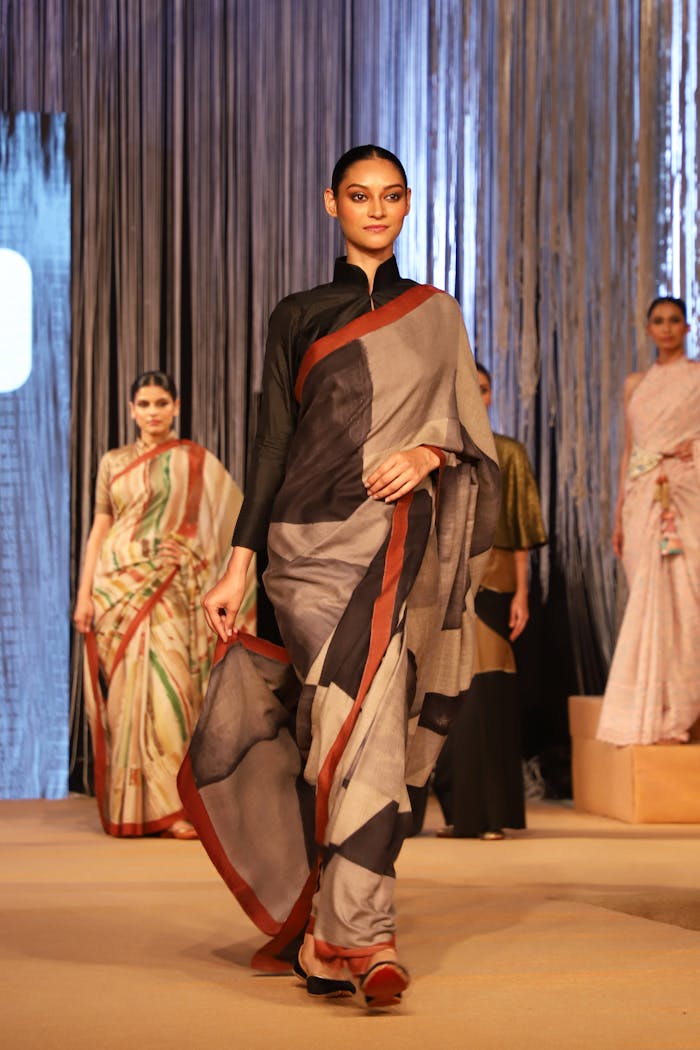 Models showcasing elegant traditional Indian sarees on a runway during a fashion show.
