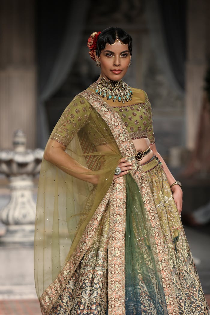 A beautiful Indian woman modeling a traditional saree in an elegant fashion pose at a runway event.
