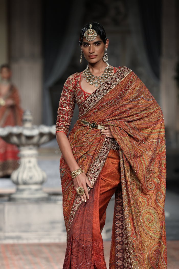 Model in ornate Indian saree showcases elegance during a high fashion runway event.